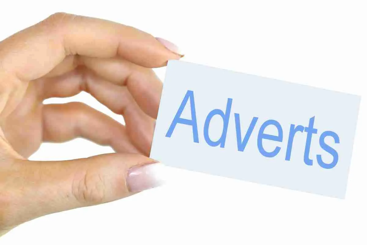 A person's hand holding a card with the word "adverts" written on it, symbolizing a focus on advertising or the concept of ad placement.