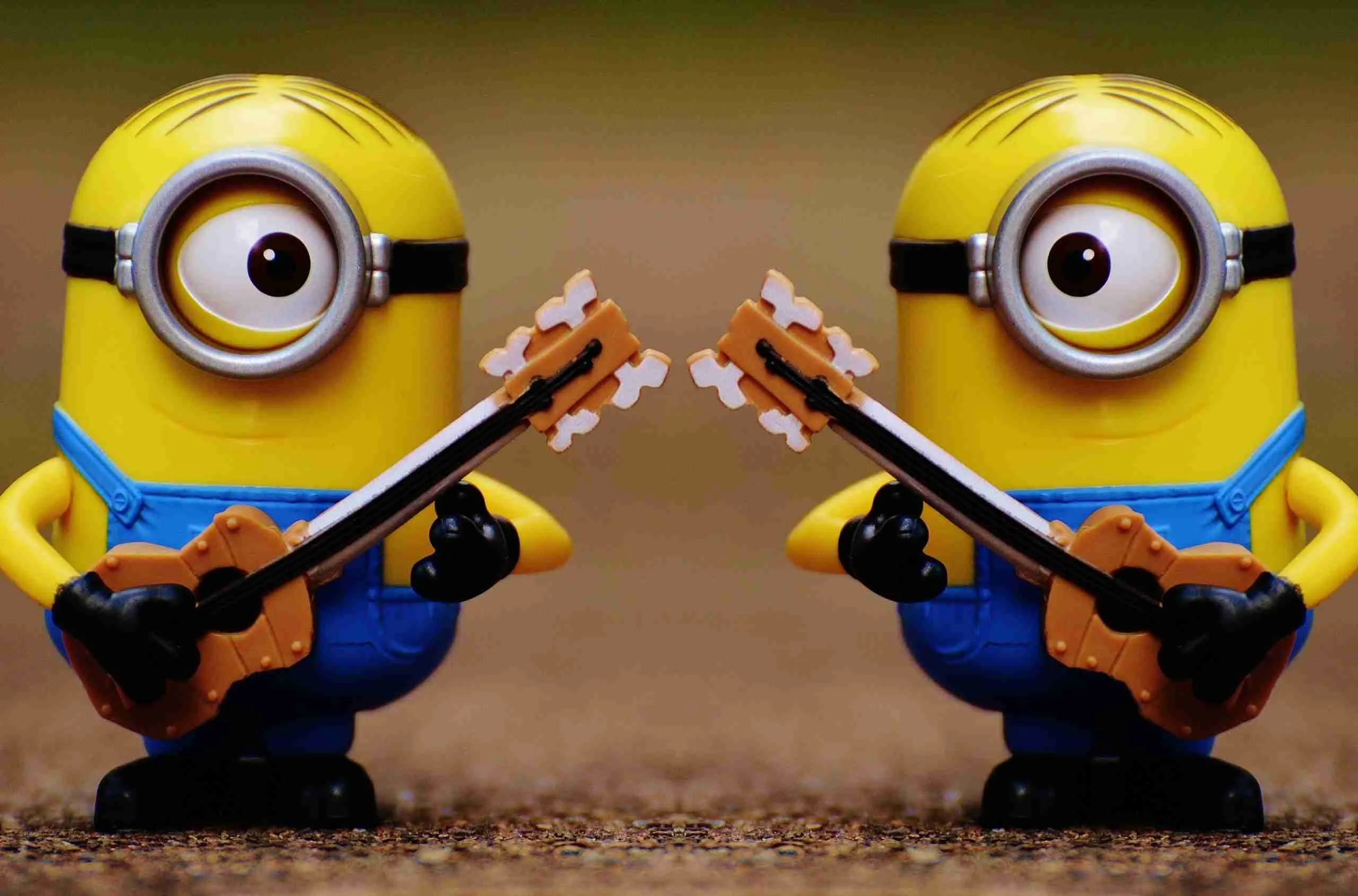 Two minion toys facing each other, each holding a guitar as if in a musical duel.