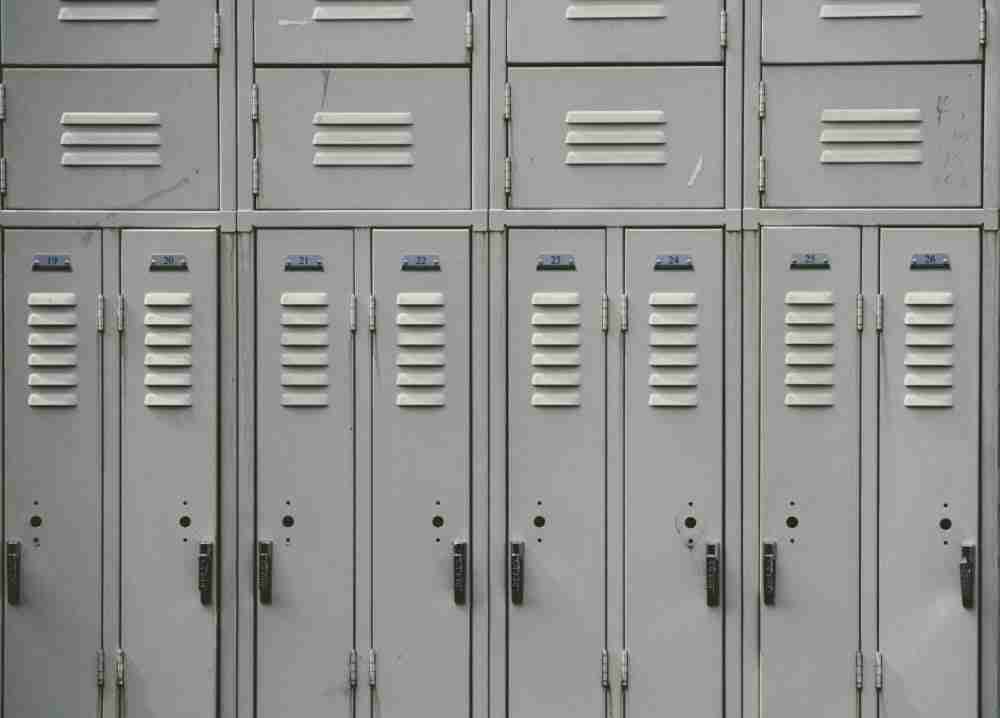 A row of closed gray metal lockers with name card slots and combination locks, suggesting a secure storage area in a school or gym setting, has been featured in a detailed MyThemeShop content locker review