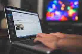 User browsing on a laptop with a colorful bokeh background, exploring what blogging is all about.
